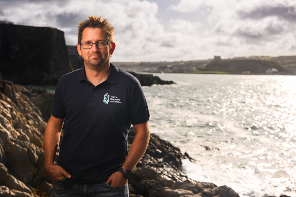 Dr Dan Smale standing on the rocky shore