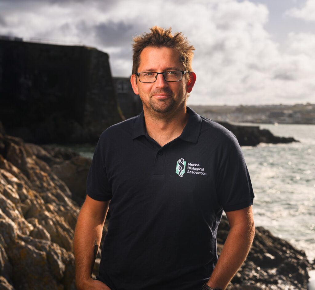 Dr Dan Smale standing on the rocky shore