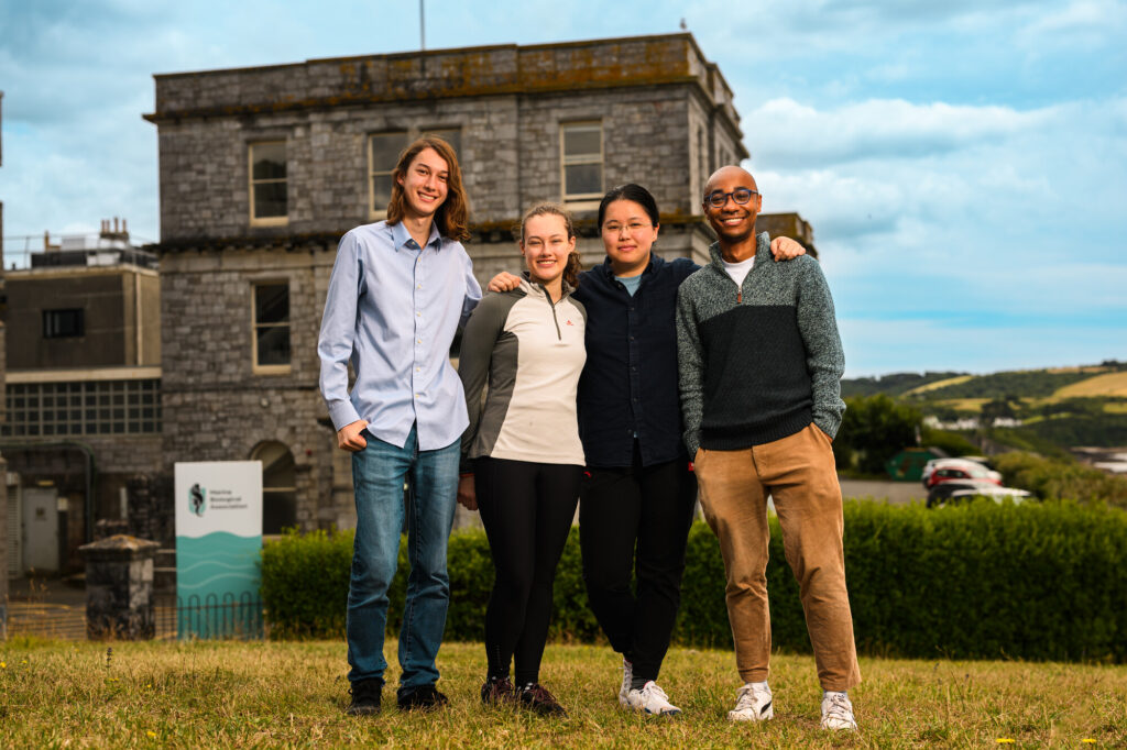 Left to right are David Hayes, undergraduate intern (Oxford); Willa Lane, PhD student (Cambridge); Peiru Chen, research assistant (Cambridge); and Victor Ajuwon, postdoctoral researcher (Cambridge) Cuttlefish Research team standing outside the MBA