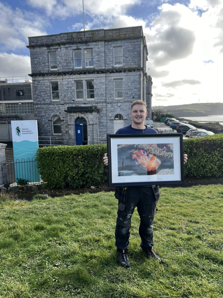 Ben Whyte, Research Facilities and Aquarium Engineer at the Marine Biological Association with his winning framed image of the Googly-eyed Tompot.